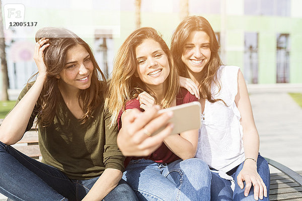 Drei glückliche Freundinnen,  die mit einem Selfie nach draußen gehen.