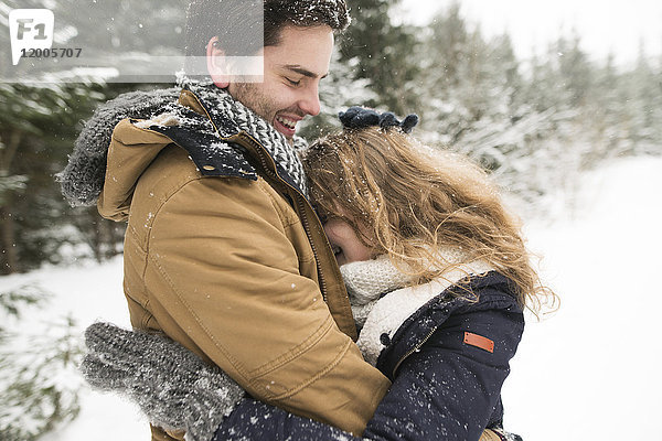Fröhliches junges Paar beim Spaß im verschneiten Winterwald
