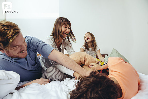 Eltern und ihre Kinder bei einer Kissenschlacht im Bett