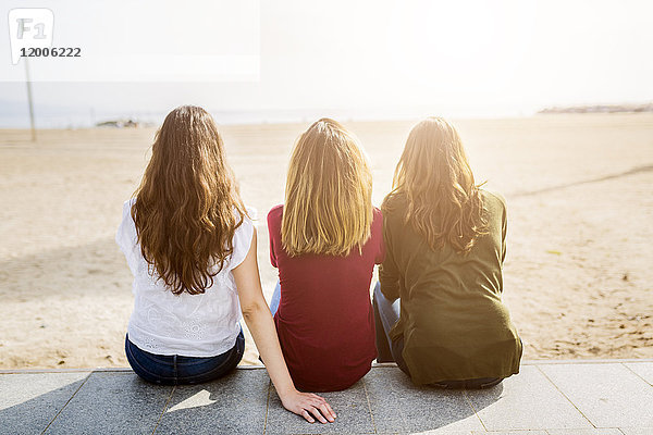 Rückansicht von drei Freundinnen am Strand