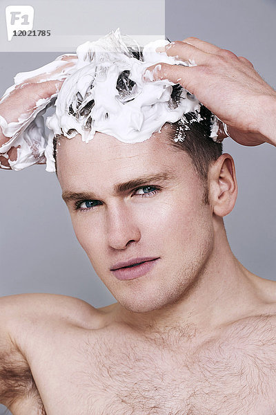 Oben-ohne-Mann,  mit Shampoo in den Haaren,  schaut in die Kamera,  ernst,  wäscht sich die Haare,  mit Schaum auf dem Kopf
