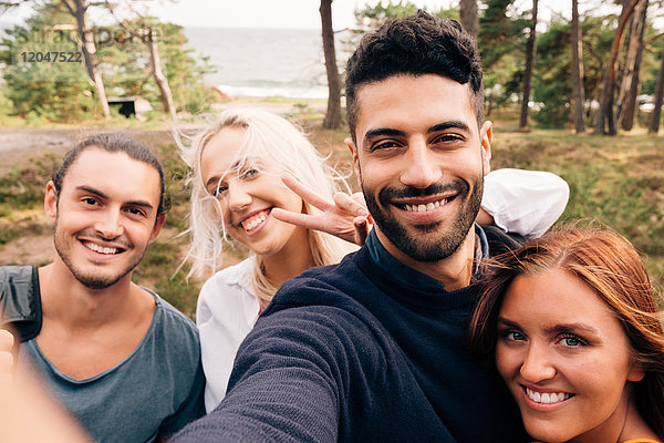 Glückliche männliche und weibliche Freunde,  die Selfie im Wald nehmen.