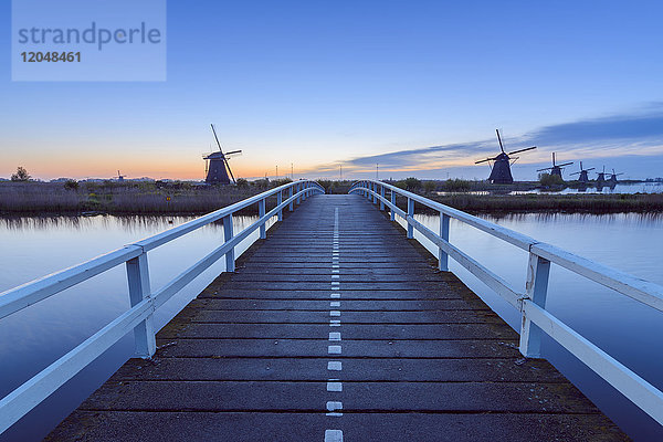 Holzbrücke mit Windmühlen in der Morgendämmerung,  Kinderdijk,  Südholland,  Niederlande