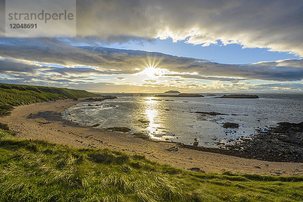 Sonnenschein über einer Bucht mit Sandstrand bei Sonnenuntergang in North Berwick am Firth of Forth in Schottland,  Vereinigtes Königreich