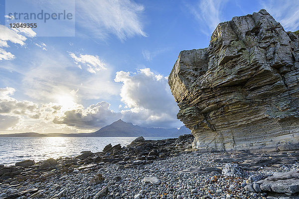 Felswand einer Meeresklippe mit wabenförmiger Verwitterung und Sonnenschein über Loch Scavaig,  Isle of Skye in Schottland,  Vereinigtes Königreich