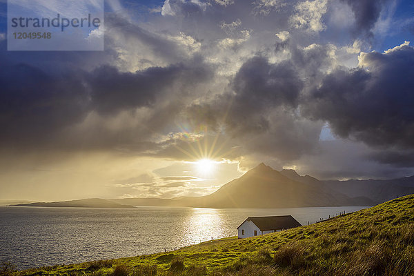 Dach eines Hauses an der schottischen Küste mit Sonne,  die durch die Wolken über Loch Scavaig,  Isle of Skye in Schottland,  scheint