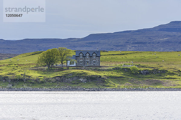 Meeresbucht mit typisch schottischem Wohnhaus in dem Dorf Dunvegan auf der Isle of Skye in Schottland,  Vereinigtes Königreich