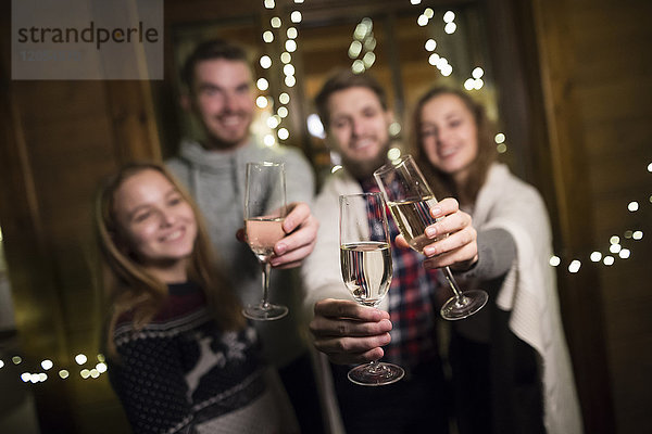 Glückliche Freunde,  die nachts im Freien Champagnergläser halten.