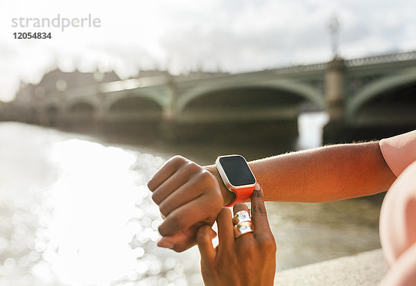 UK,  London,  Nahaufnahme der Frau mit ihrer Smartwatch bei der Westminster Bridge