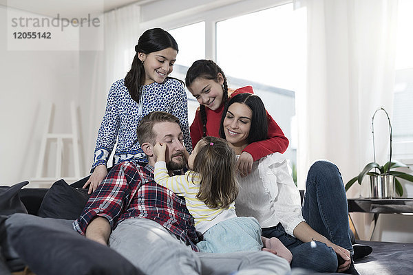 Eltern und drei Töchter auf Sofa im Wohnzimmer