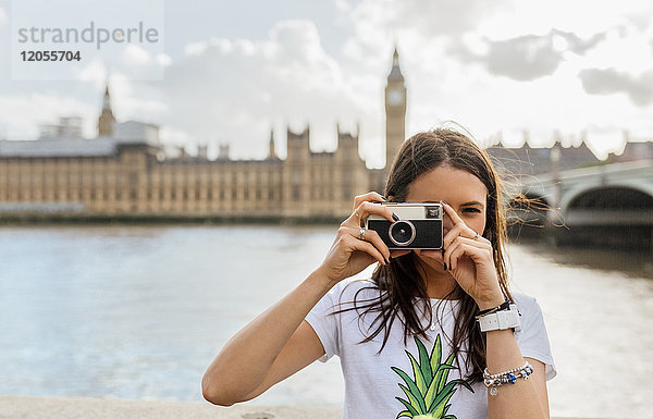 UK,  London,  schöne Frau beim Fotografieren nahe der Westminster Bridge