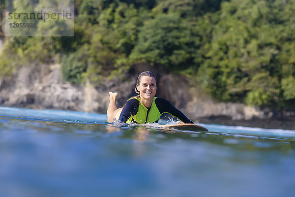 Indonesien,  Bali,  lächelnde Frau auf dem Surfbrett liegend