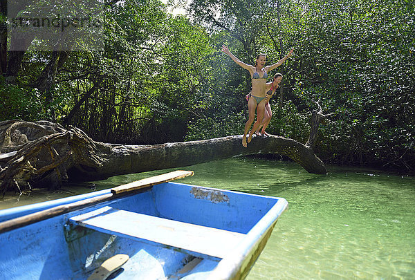 Dominikanische Republik,  Samana,  zwei Frauen beim Sprung ins Wasser in einer Mangrovenlagune