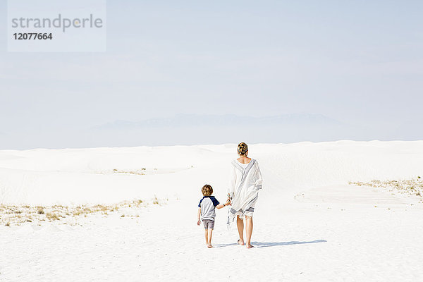 Kaukasische Mutter und Sohn gehen im Sand spazieren