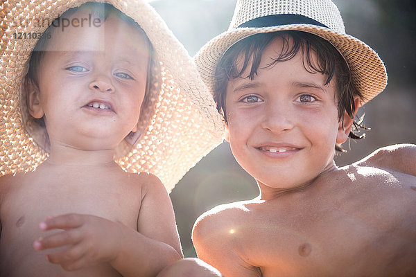 Porträt eines Jungen und eines kleinen Bruders am Strand mit Sonnenhüten,  Begur,  Katalonien,  Spanien