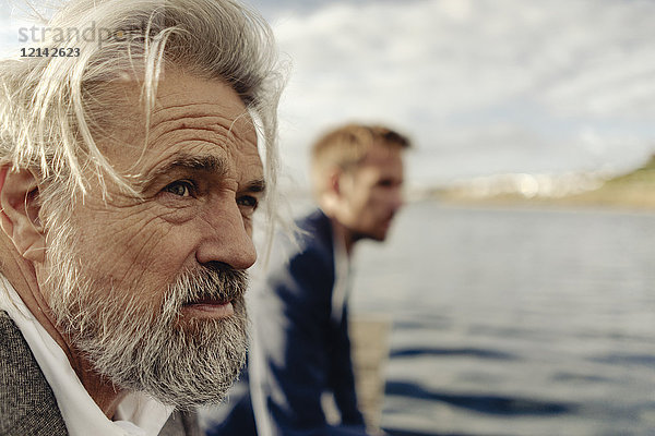 Porträt eines ernsthaften älteren Mannes an einem See mit Mann im Hintergrund