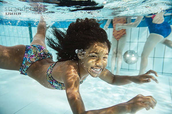 Porträt des lächelnden Mädchens unter Wasser im Schwimmbad