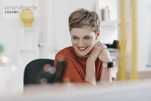 Porträt einer lächelnden Frau am Schreibtisch im Büro