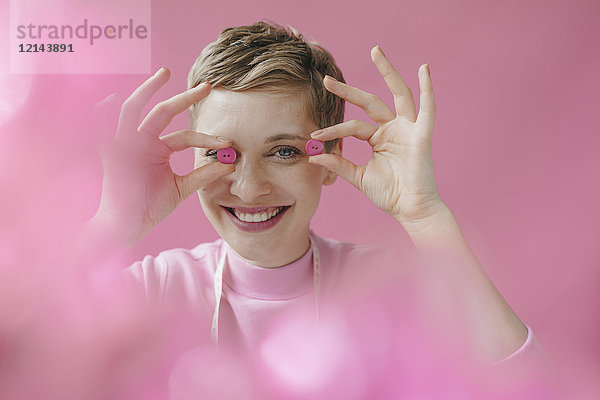 Porträt einer fröhlichen Schneiderin mit rosa Knöpfen