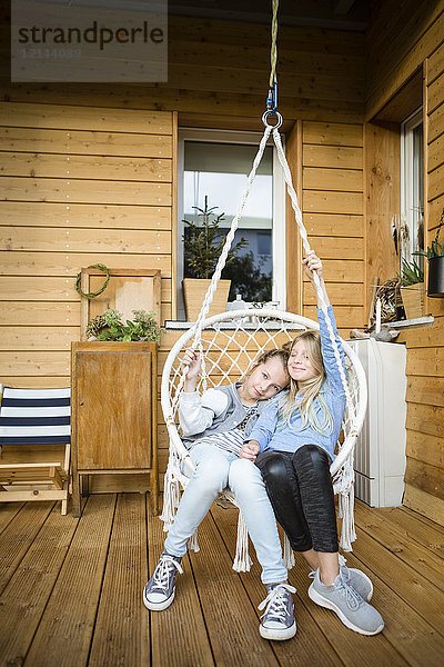 Zwei Mädchen im Hängestuhl auf der Veranda
