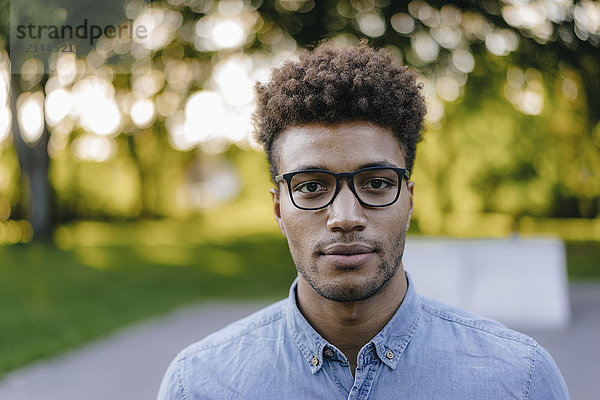Porträt eines jungen Mannes mit Brille im Park