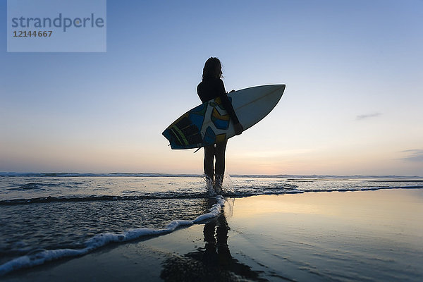 Indonesien,  Bali,  Junge Frau mit Surfbrett