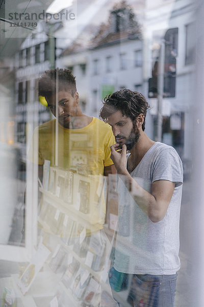 Zwei Freunde in der Stadt suchen im Schaufenster einer Buchhandlung