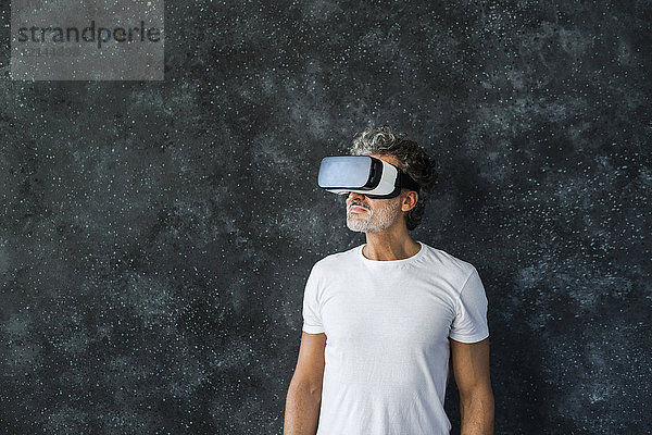 Erwachsener Mann,  der durch die VR-Brille schaut