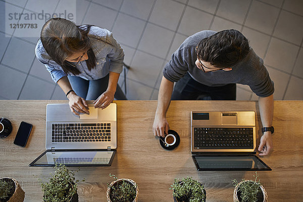 Draufsicht auf junge Frau und Mann in einem Café mit Laptops zur Diskussion