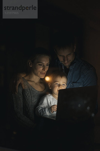Familie mit Laptop im Dunkeln