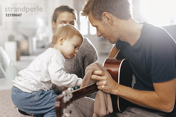 Kleines Mädchen untersucht Vaters Gitarre zu Hause