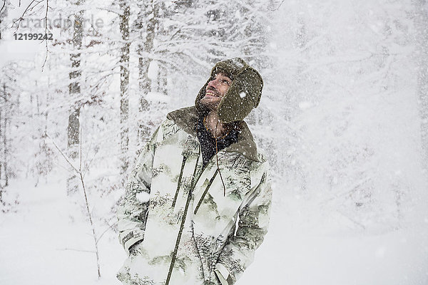 Glücklicher Mann in Camouflage-Jacke im Winterwald