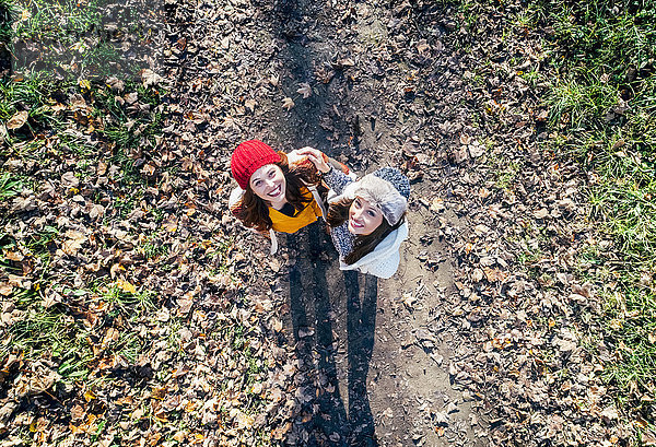 Zwei glückliche Frauen,  die auf einem herbstlichen Waldweg stehen.