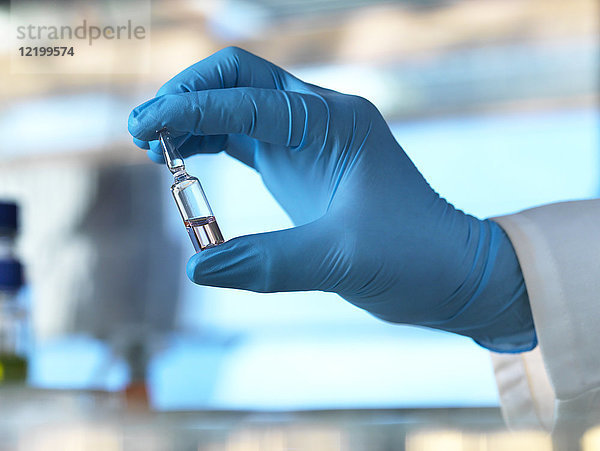 Wissenschaftler hält ein Fläschchen mit einer Flüssigkeit im Labor