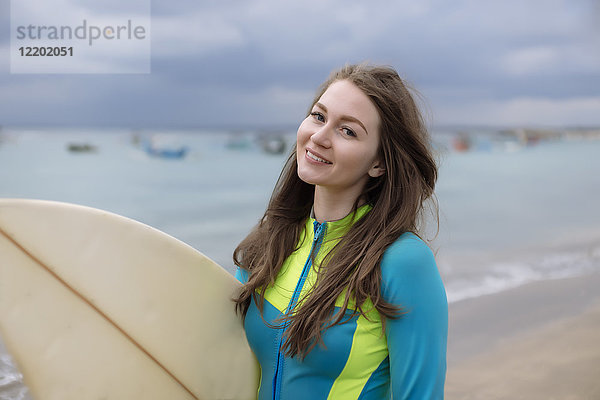 Indonesien,  Bali,  junge Frau mit Surfbrett