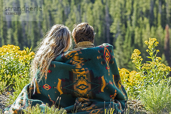 Kaukasisches Paar,  eingewickelt in eine Decke,  bewundert eine schöne Landschaft