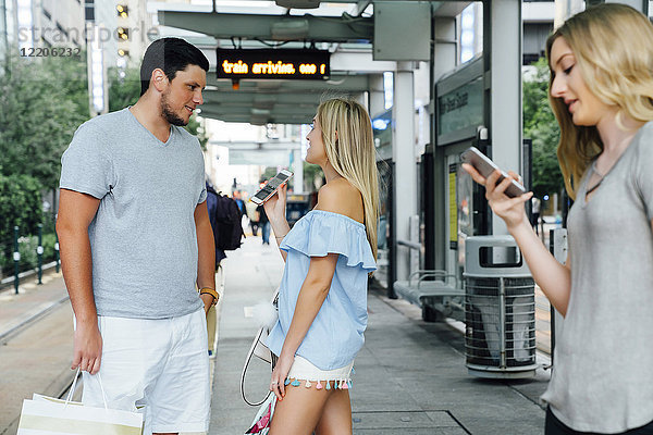 Kaukasische Frau zeigt einem Mann am Bahnhof ihr Handy