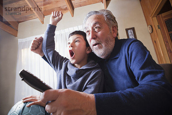 Hispanischer Großvater und Enkel jubeln über ein Fußballspiel im Fernsehen