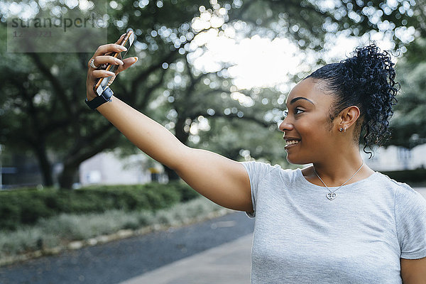 Lächelnde schwarze Frau,  die für ein Handy-Selfie posiert