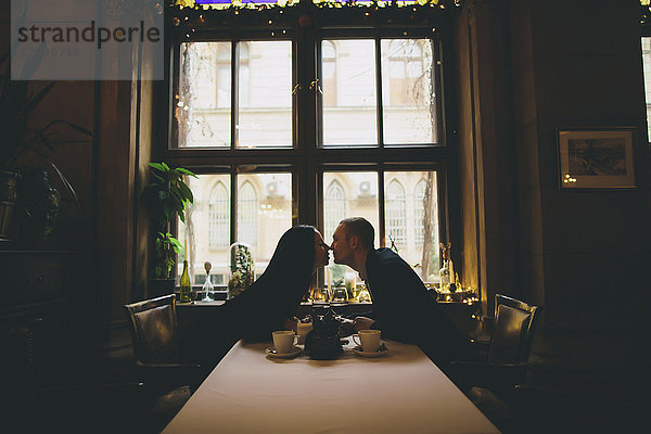 Kaukasisches Paar sitzt am Tisch und reibt sich die Nasen
