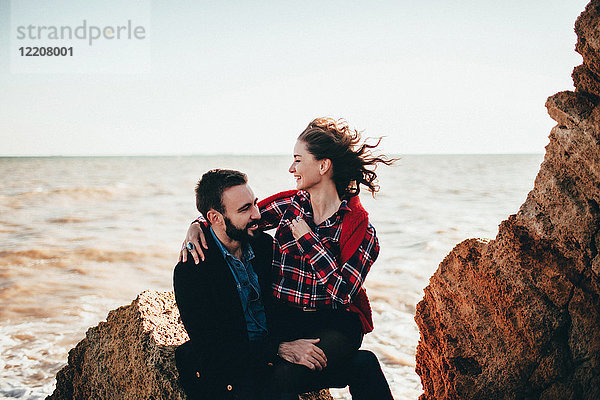 Romantisches Paar mittlerer Erwachsener auf Strandfelsen sitzend,  Oblast Odessa,  Ukraine