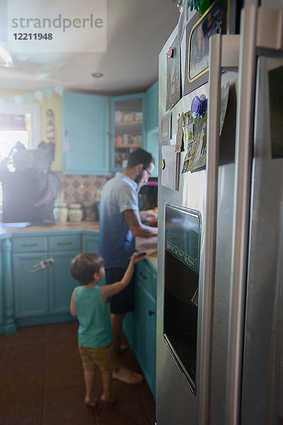 Junge steht hinter dem Vater an der Küchentheke