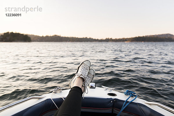 Persönliche Perspektive Frau Bootfahrt mit Füßen oben auf dem ruhigen See