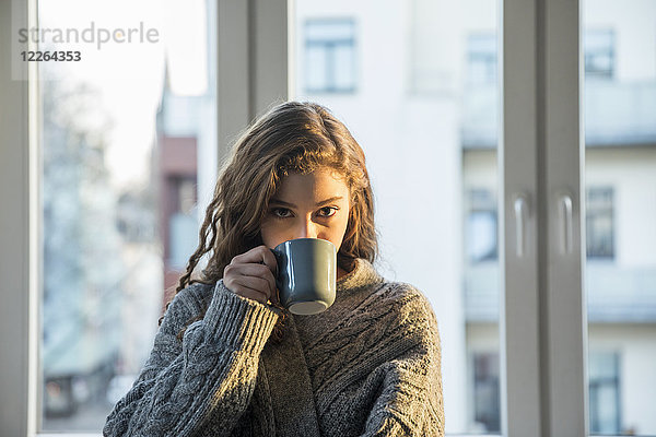 Porträt eines jungen Mädchens beim Kaffeetrinken zu Hause