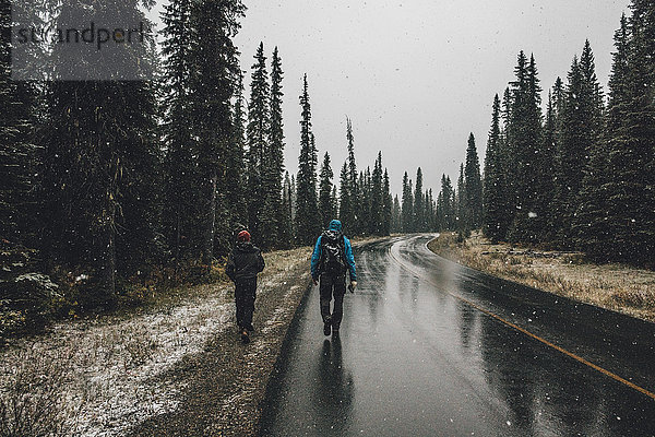 Kanada,  British Columbia,  Yoho Nationalpark,  zwei Männer beim Wandern auf der Yoho Valley Road bei Schneefall