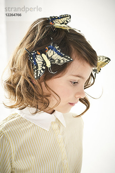 Porträt eines kleinen Mädchens mit Spielzeug-Schmetterlingen im Haar