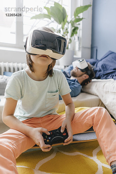Junge und Vater mit VR-Brille beim Videospiel zu Hause