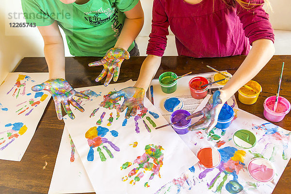 Mädchen und Junge spielen mit Fingerfarbe,  Handabdrücke