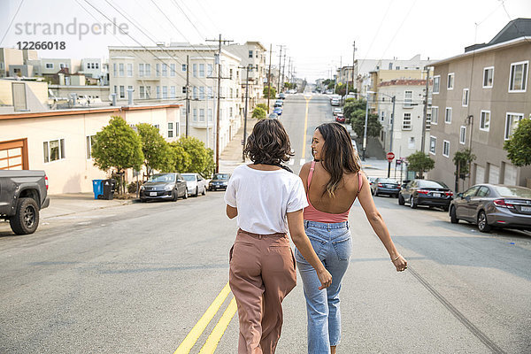Zwei junge Frauen,  die die Straße entlang gehen.