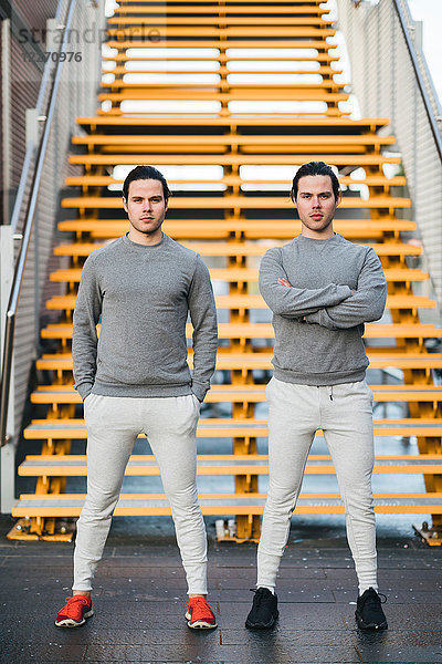 Junge erwachsene männliche Zwillinge,  die zusammen trainieren,  Treppenhaus-Portrait